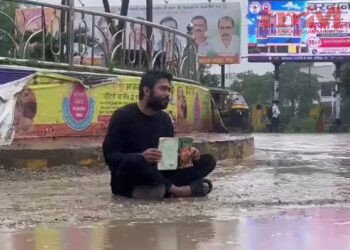 रीवा में युवक का अनोखा प्रदर्शन, किताब लेकर सड़क पर बरसते पानी में बैठा