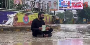 रीवा में युवक का अनोखा प्रदर्शन, किताब लेकर सड़क पर बरसते पानी में बैठा